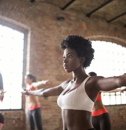 close up of woman in workout bra doing yoga with class in industrial room