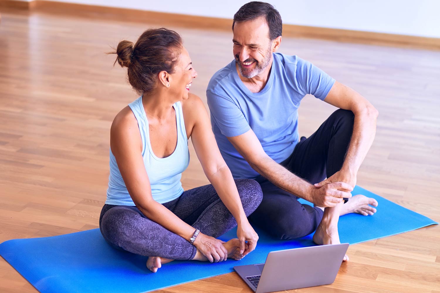 couple sits on yoga mat ready for pilates class over video call