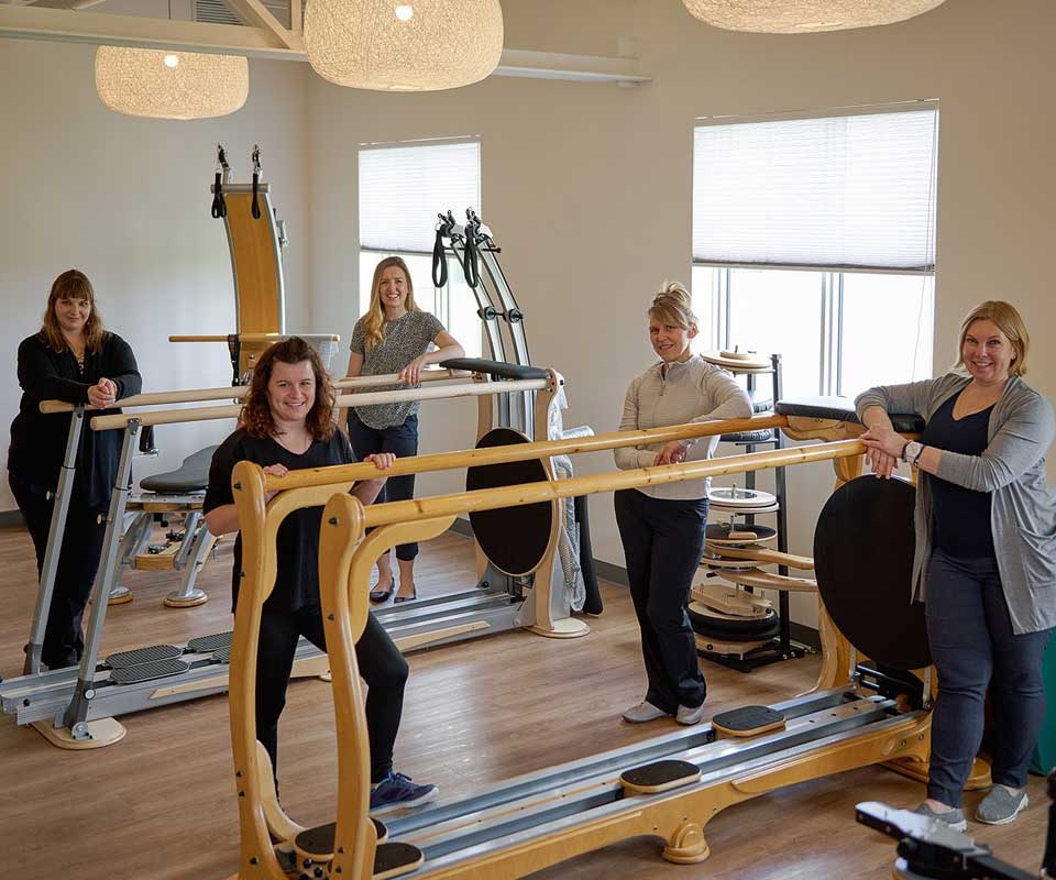 five women standing around some equipment in a physio therapy clinic