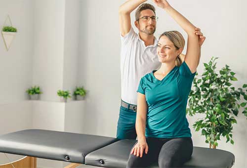photo of a man assisting a woman in doing stretches.