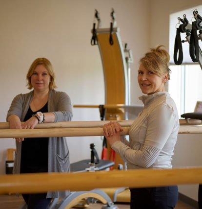 two women standing next to balance beams in a gym