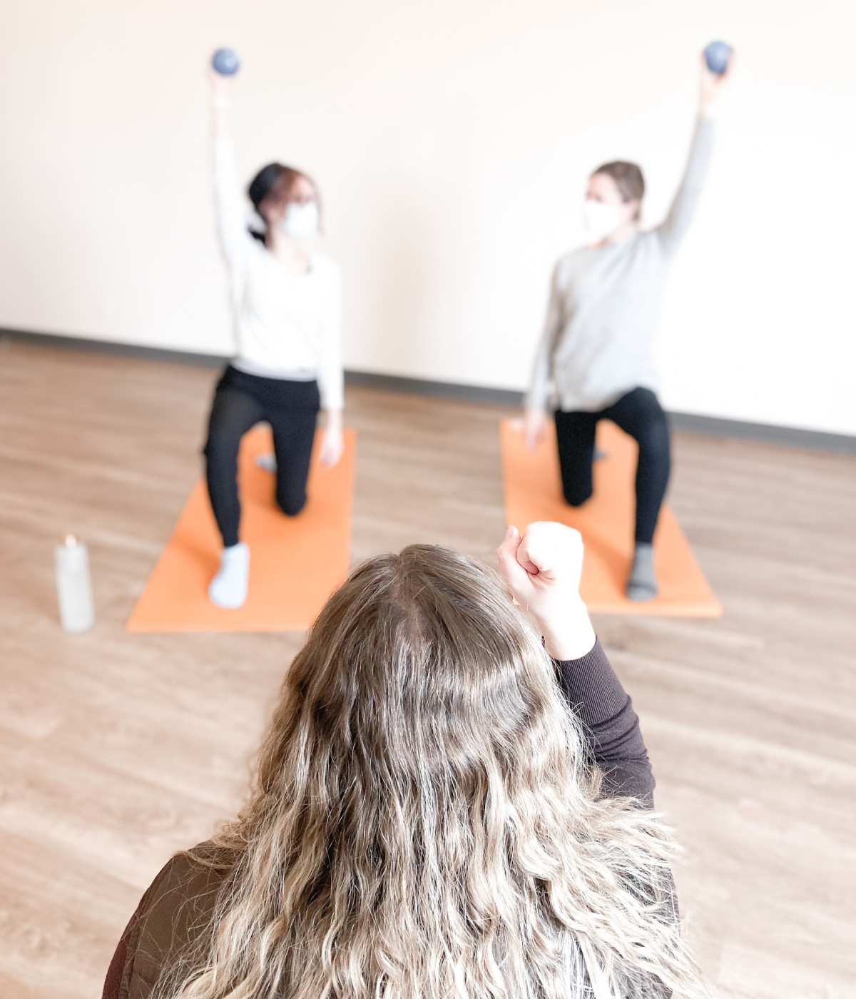 back view of a woman's head with 2 people stretching in the background