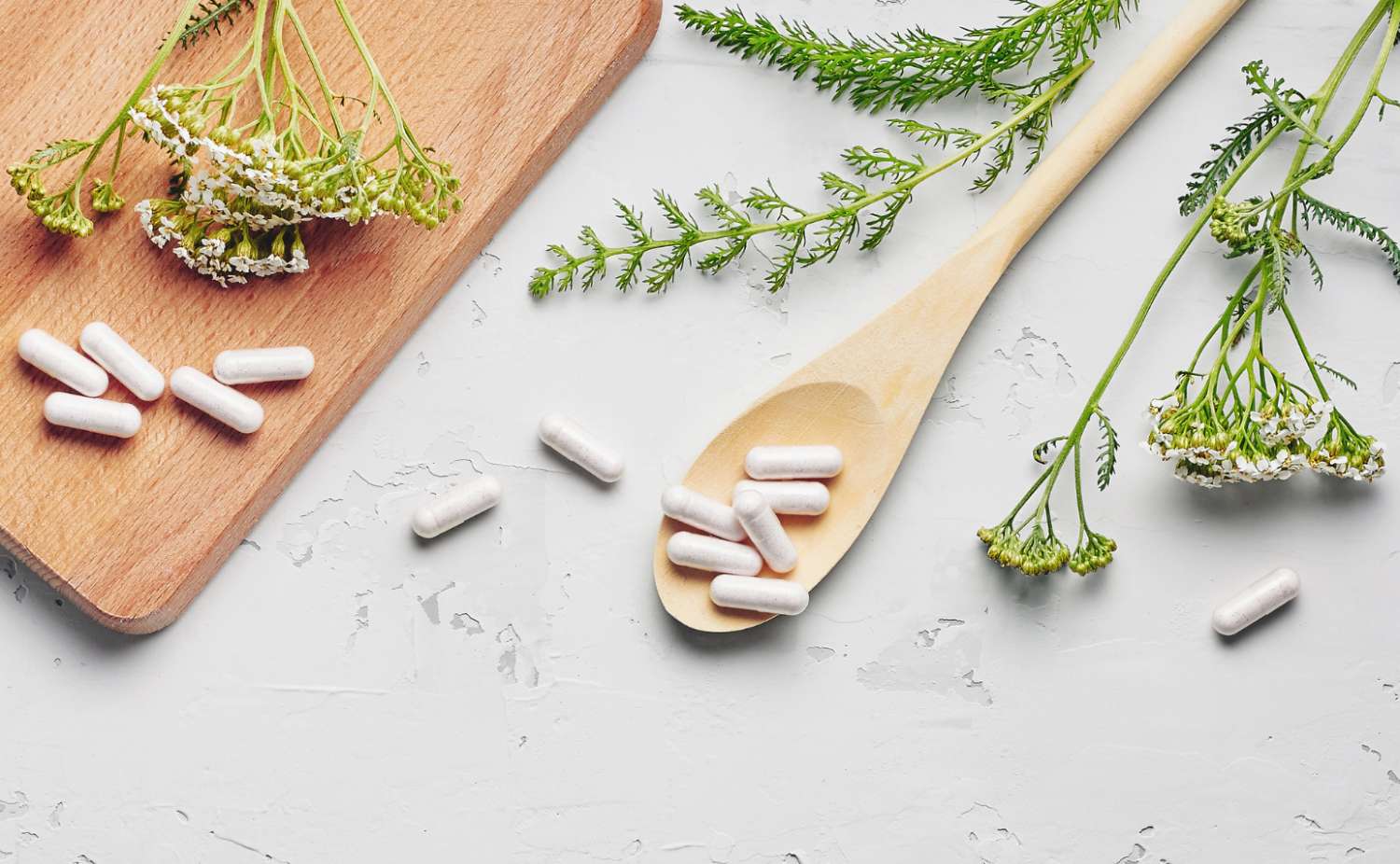 a wooden spoon holding white capsules