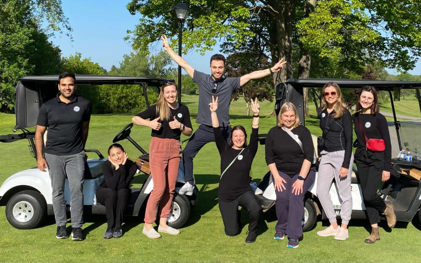 a group of people posing around a golf cart