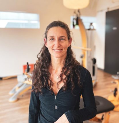 a woman standing in a gym with a smile on her face