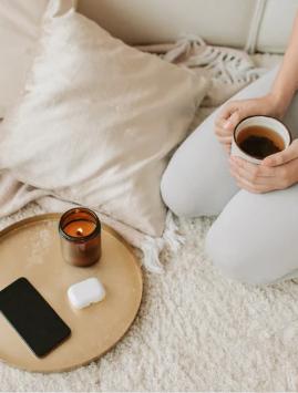 a woman sitting on a bed holding a cup of coffee