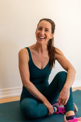 a woman sitting on a yoga mat smiling