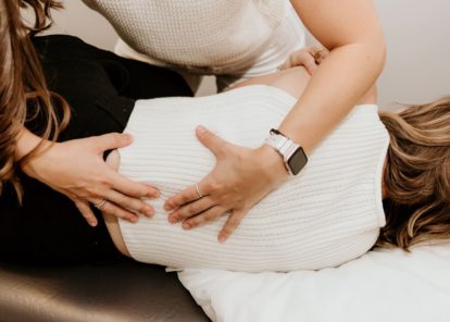 Physiotherapist performing manual therapy on client on treatment table.