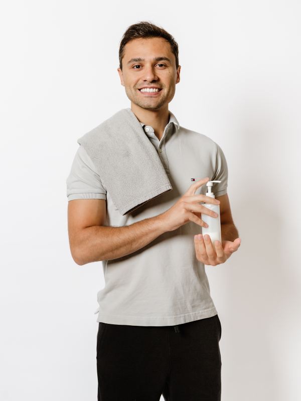 a man holding a bottle of lotion and a towel