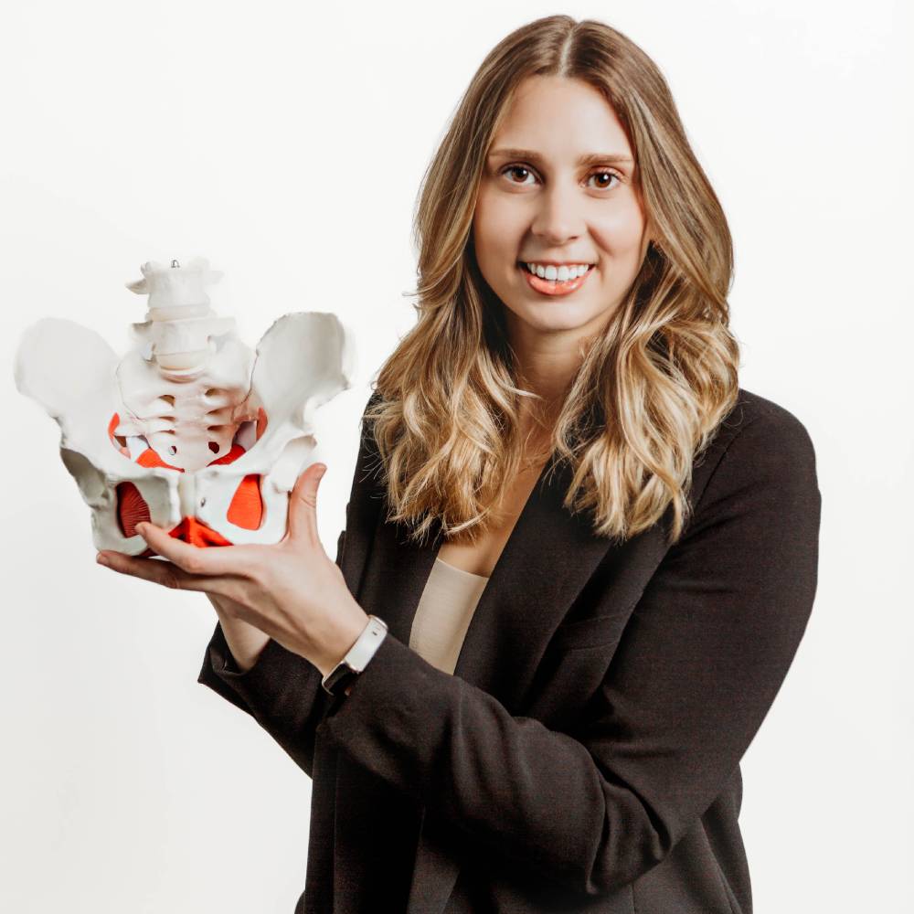a woman holdin a plastic model of a pelvis